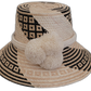Handmade Wayuu bohemian straw hat with cream pompoms and black-beige geometric woven patterns.


