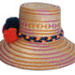 Boho chic artisan straw hat with bold geometric pattern and vibrant colorful pompom trio.