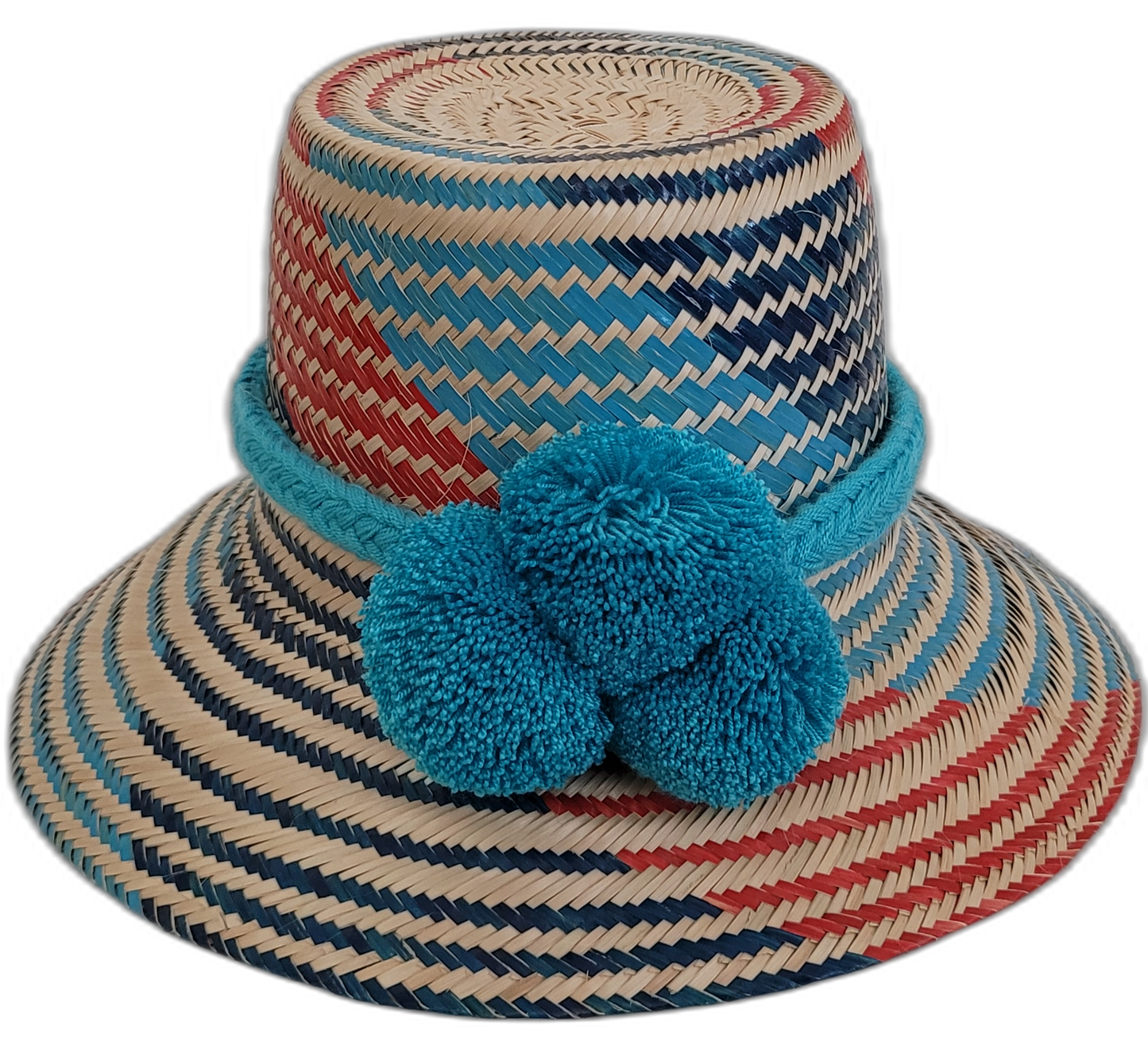 Colorful bohemian straw hat with blue, red, and natural tones, handmade by Wayuu artisans, featuring bold pom-poms.

