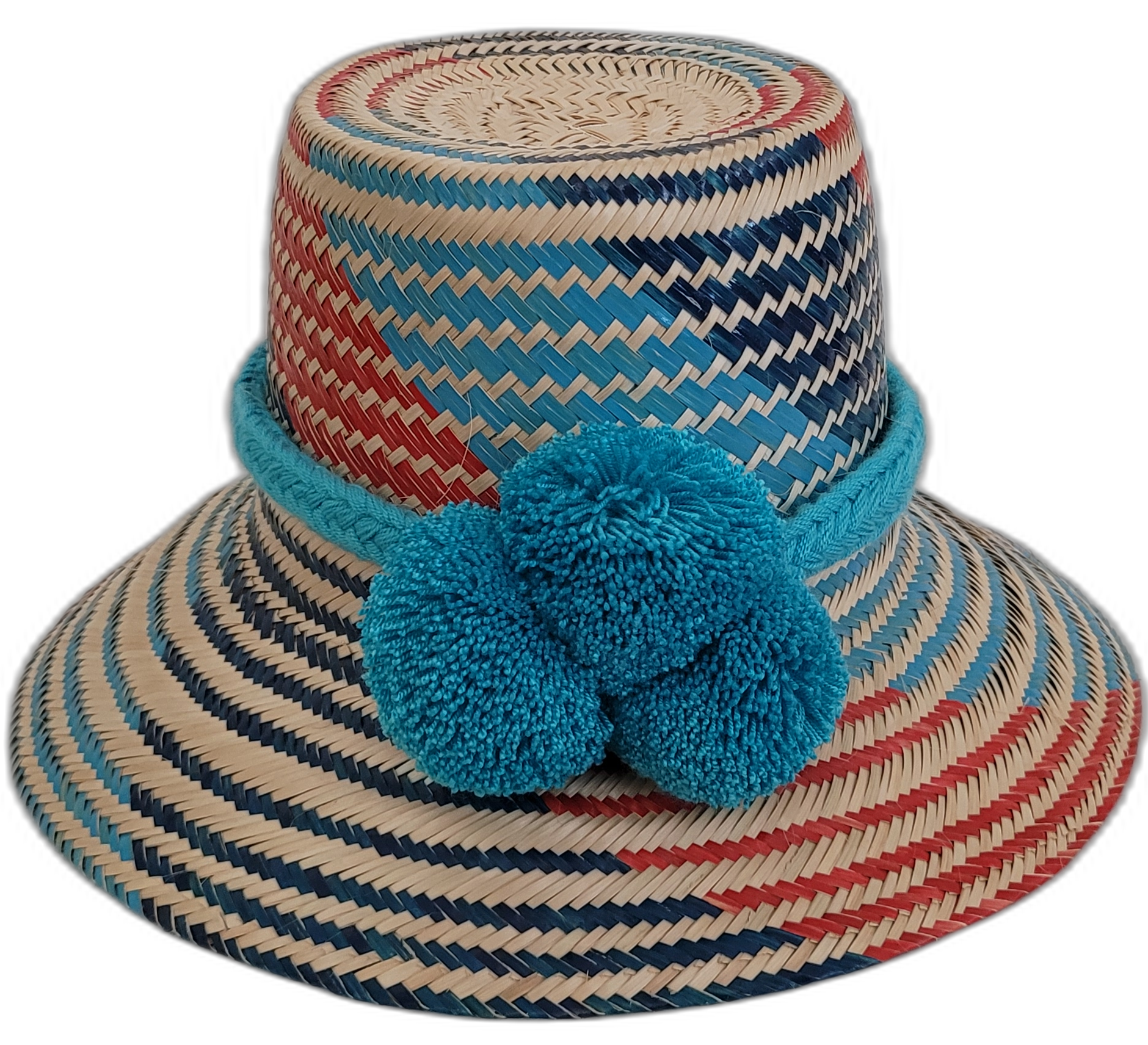 Colorful bohemian straw hat with blue, red, and natural tones, handmade by Wayuu artisans, featuring bold pom-poms.

