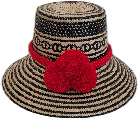 Handmade Wayuu bohemian straw hat with red pompoms and bold black-beige woven patterns.

