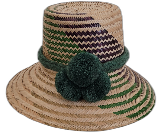 Handmade Wayuu bohemian straw hat with deep green pompoms and green-purple beige woven patterns.

