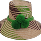 Handmade Wayuu bohemian straw hat with bright green pompoms and green-purple-beige woven patterns.

