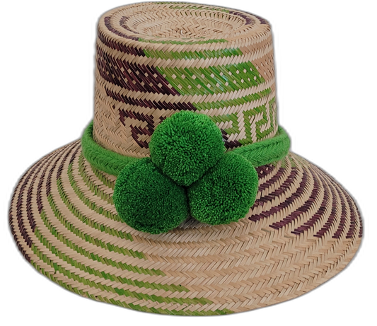 Handmade Wayuu bohemian straw hat with bright green pompoms and green-purple-beige woven patterns.