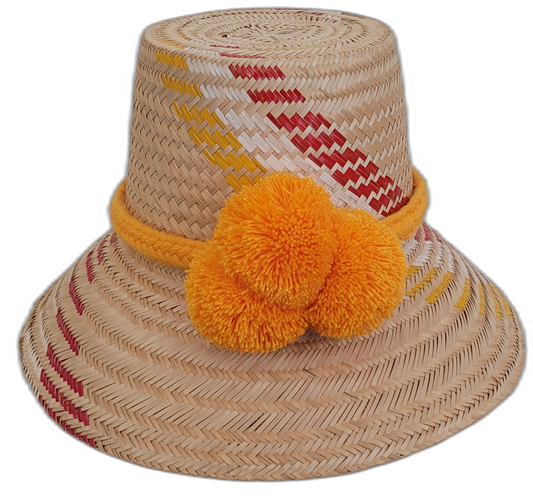 Handmade Wayuu bohemian straw hat with bright orange pompoms and yellow-red woven patterns.

