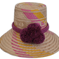 Handmade Wayuu bohemian straw hat with pink, yellow, and purple patterns and large pompoms.

