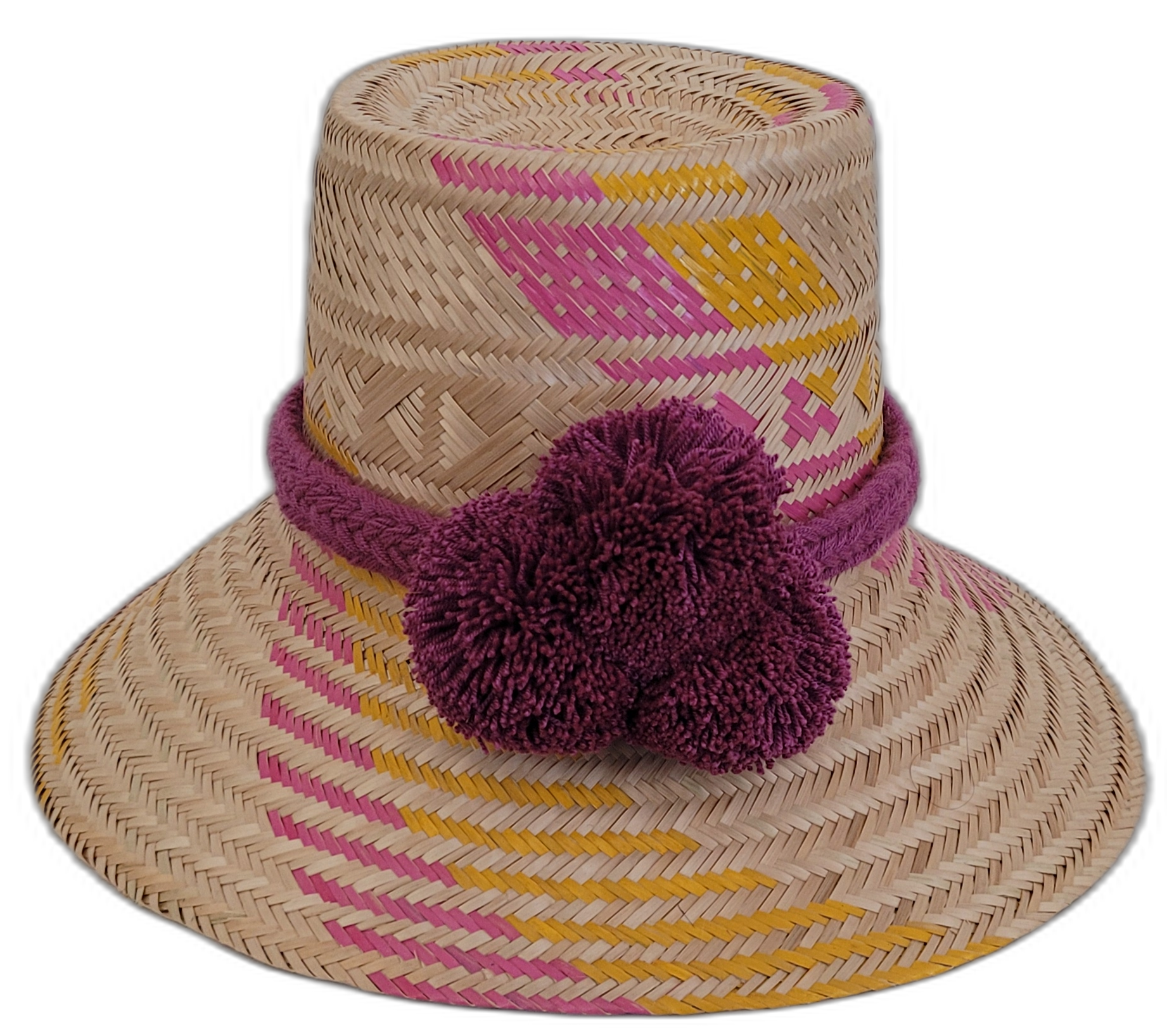 Handmade Wayuu bohemian straw hat with pink, yellow, and purple patterns and large pompoms.


