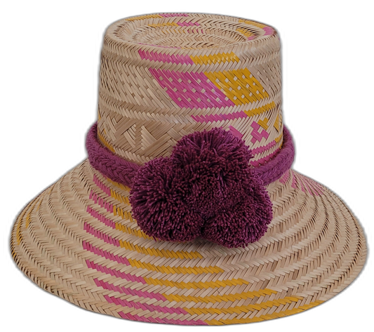 Handmade Wayuu bohemian straw hat with pink, yellow, and purple patterns and large pompoms.

