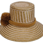 Boho-chic Wayuu straw hat featuring golden-brown pompoms and handwoven details.

