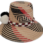 Artisan Wayuu hat with striking black-and-white pompoms and detailed red patterns.

