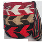 Artisan-crafted Wayuu shoulder bag with red, tan, and black color blocks and crochet tassels — a bold, handmade boho accessory.