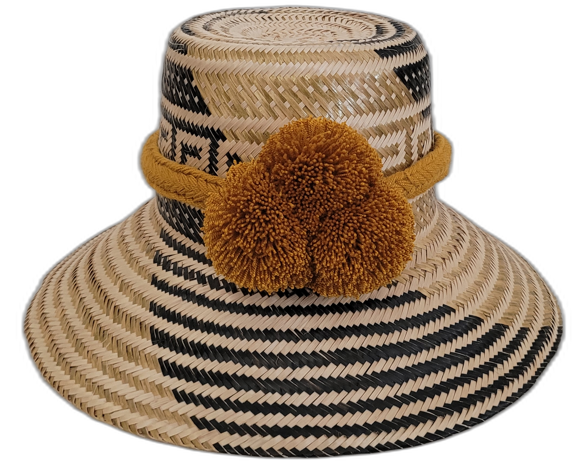 Handmade bohemian straw hat with black pattern and mustard pompoms, crafted by Wayuu artisans.

