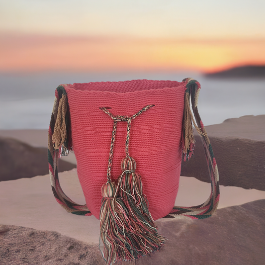 Handmade Wayuu crochet bag in solid pink with long multicolor tassels and a wide artisan strap — a vibrant boho-chic statement piece.