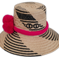 Boho Wayuu artisan straw hat in black and natural tones with bold pink pompoms.

