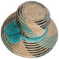 Wayuu hat with vibrant turquoise pompoms and contrasting black geometric designs.