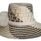 Black and beige bohemian straw hat with bold artisan detail and culturally significant white pompoms.