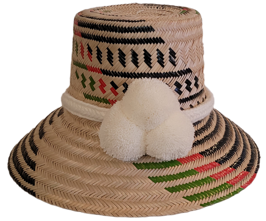 Handmade Wayuu straw hat with white pompom and red-green-black patterns, perfect Boho chick accessory.