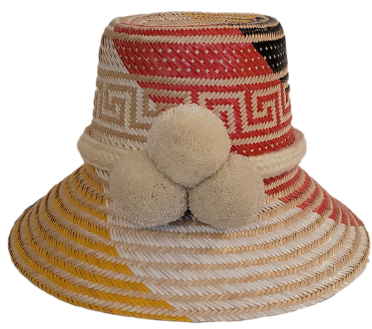 Handmade Wayuu straw hat with white pompoms and red, yellow, and black geometric design.