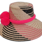 Colorful boho straw hat, crafted by Wayuu artisans, showing intricate pink and black woven patterns and handmade pompoms.