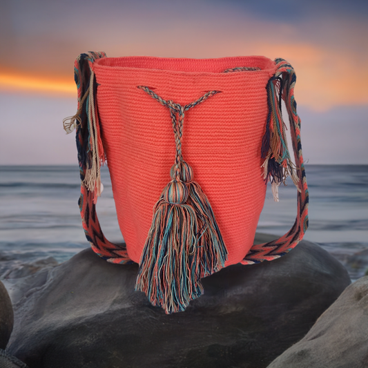 Boho-chic Wayuu crochet bag in coral with multicolor tassels and artisan chevron strap — a bold, handmade accessory full of color and style.