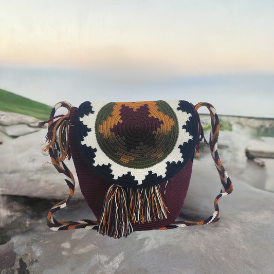 Handmade Wayuu crochet flap bag in rich earth tones with mustard, olive, and ivory sunburst design — artisan boho-chic accessory with fringe.