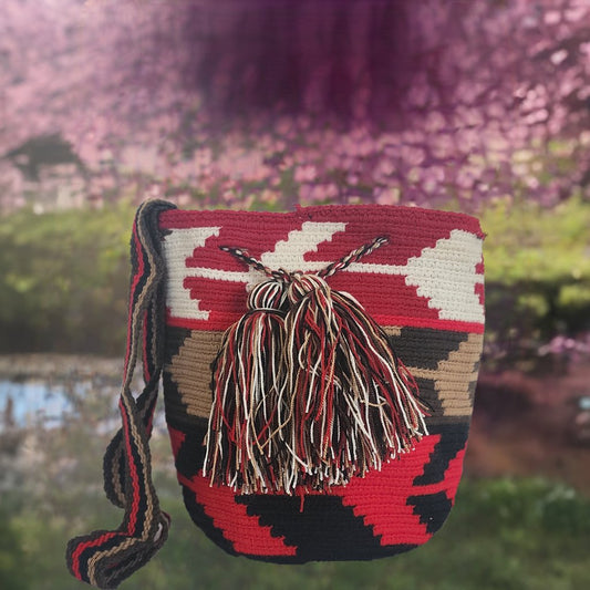 Handmade Wayuu crochet bag with bold red, black, and cream tribal pattern and tassels — artisan boho-chic style with strong visual impact.