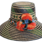 Handmade Wayuu straw hat with green, blue geometric pattern and orange pompoms.Bohemian straw hat with bright pompoms and tribal diamond designs

