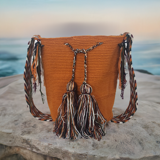 Boho-chic handmade Wayuu crochet bag in burnt orange with long artisan tassels and a bold patterned strap — perfect for colorful, creative souls.