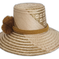 Natural straw Wayuu hat with soft olive patterns and brown pompom accents