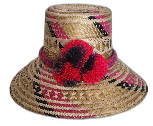 Handmade Wayuu straw hat with red and black pompoms and woven pink patterns