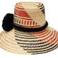 "Colorful handmade hats by Wuitusu, crafted from Iraca palm fibers by the Wayuu tribe, adorned with cultural pompoms."