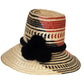 Colorful handmade straw hat by Wuitusu, woven from Iraca palm fibers, adorned with symbolic pompoms.