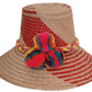 Colorful handmade straw hat with rainbow pompoms and red woven pattern