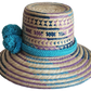 "Colorful handmade Wayuu hat crafted from Iraca palm fibers, adorned with meaningful pompoms, adjustable fit."