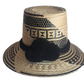 "Colorful handmade Wayuu hat crafted from Iraca palm fibers with culturally significant pompoms, offering sun protection and 