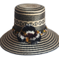 "Colorful handmade Wayuu hat crafted from Iraca palm with decorative pompoms, symbolizing wealth in Wayuu culture."