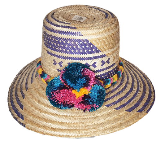 "Colorful handmade Wayuu hat with decorative pompoms, crafted from Iraca palm fibers by Wuitusu artisans."