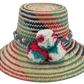 "Colorful handmade Wayuu hat with decorative pompoms, crafted from Iraca palm fibers, offering style and sun protection."