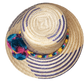 "Colorful handmade Wayuu hat with decorative pompoms, crafted from Iraca palm fibers by Wuitusu artisans."