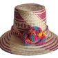 "Colorful handmade Wayuu hat woven from Iraca palm fibers, adorned with culturally significant pompoms, offering adjustable f