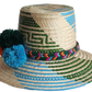 "Colorful handmade Wayuu hat woven from Iraca palm fibers, featuring decorative pompoms and offering adjustable fit."