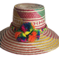 "Colorful handmade Wayuu hat woven from Iraca palm with adjustable fit and cultural pompoms, supporting Wayuu artisans."