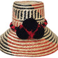 "Colorful handmade Wayuu hats from Wuitusu, crafted with Iraca palm fibers, featuring decorative pompoms."