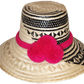 "Colorful handwoven Wayuu hat from Wuitusu, crafted with Iraca palm fibers and decorated with cultural pompoms."