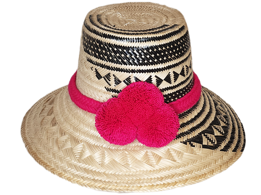 "Colorful handwoven Wayuu hat from Wuitusu, crafted with Iraca palm fibers and decorated with cultural pompoms."