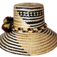 "Colorful handwoven Wayuu hat made from Iraca palm, adorned with cultural pompoms for prosperity, adjustable to fit all sizes