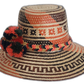 Artisan boho straw hat in natural straw with red and black patterns and colorful pompoms.