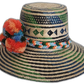 Artisan straw hat featuring blue and green weave with vibrant multicolor pompoms.

