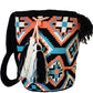Bohemian crochet bag, handmade by Wayuu artisans, featuring black and coral weave, turquoise details, crossbody strap, and large tassels.