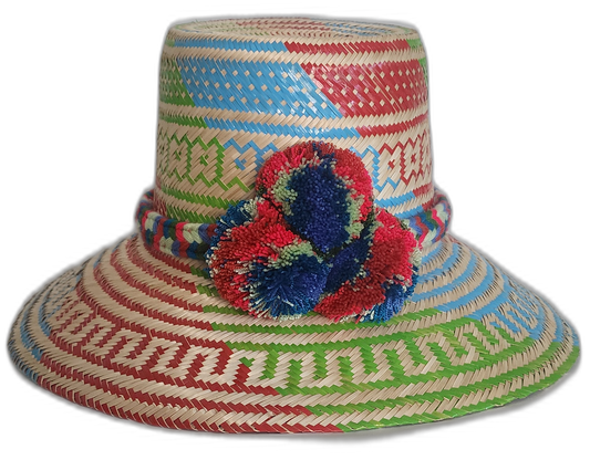 Handmade Wayuu boho straw hat with vibrant red, blue, and green woven patterns and bold pompom accents.